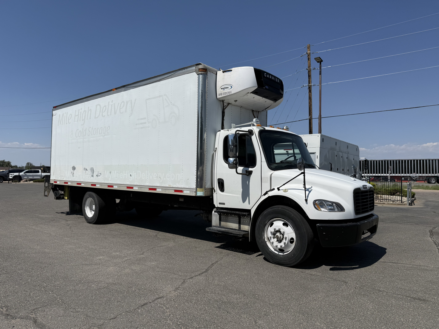 Freightliner M2106 refrigerated truck with curbside view showing cargo box and refrigeration unit