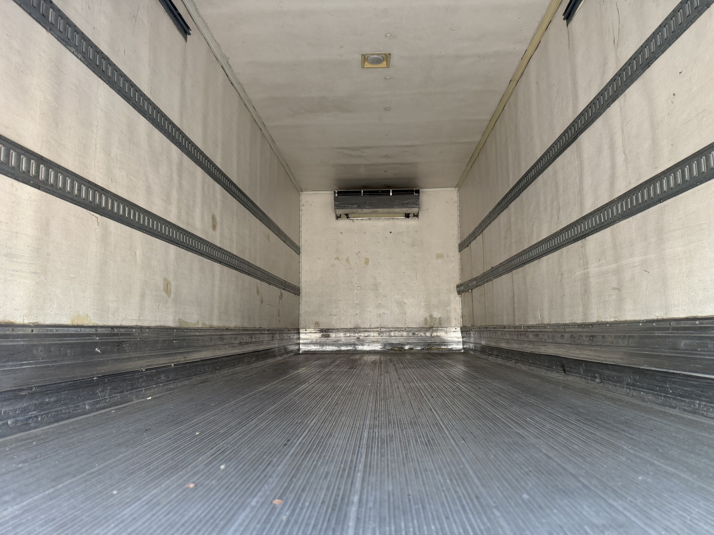 Trailer interior showing refrigerated box with ribbed side walls and floor, ceiling vent at back, and side rails.