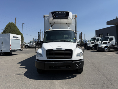 Front view of a white 2008 Freightliner M2106 refrigerated truck with Carrier unit on the roof, black bumper, and surrounding trucks in a dealership lot.