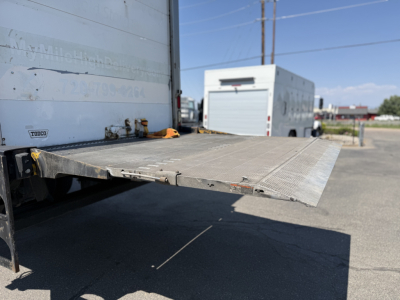 Freightliner M2106 rear with a lowered aluminum loading ramp and refrigerated body pedal, showing the side and back of the trailer.