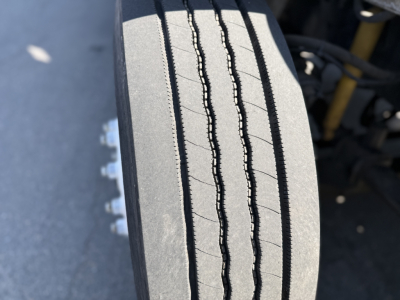 Tire tread close-up on Freightliner M2106 chassis showing front wheel with deep tread grooves.