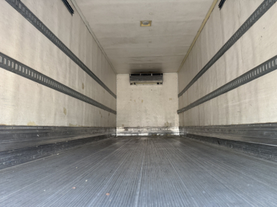 Trailer interior showing refrigerated box with ribbed side walls and floor, ceiling vent at back, and side rails.