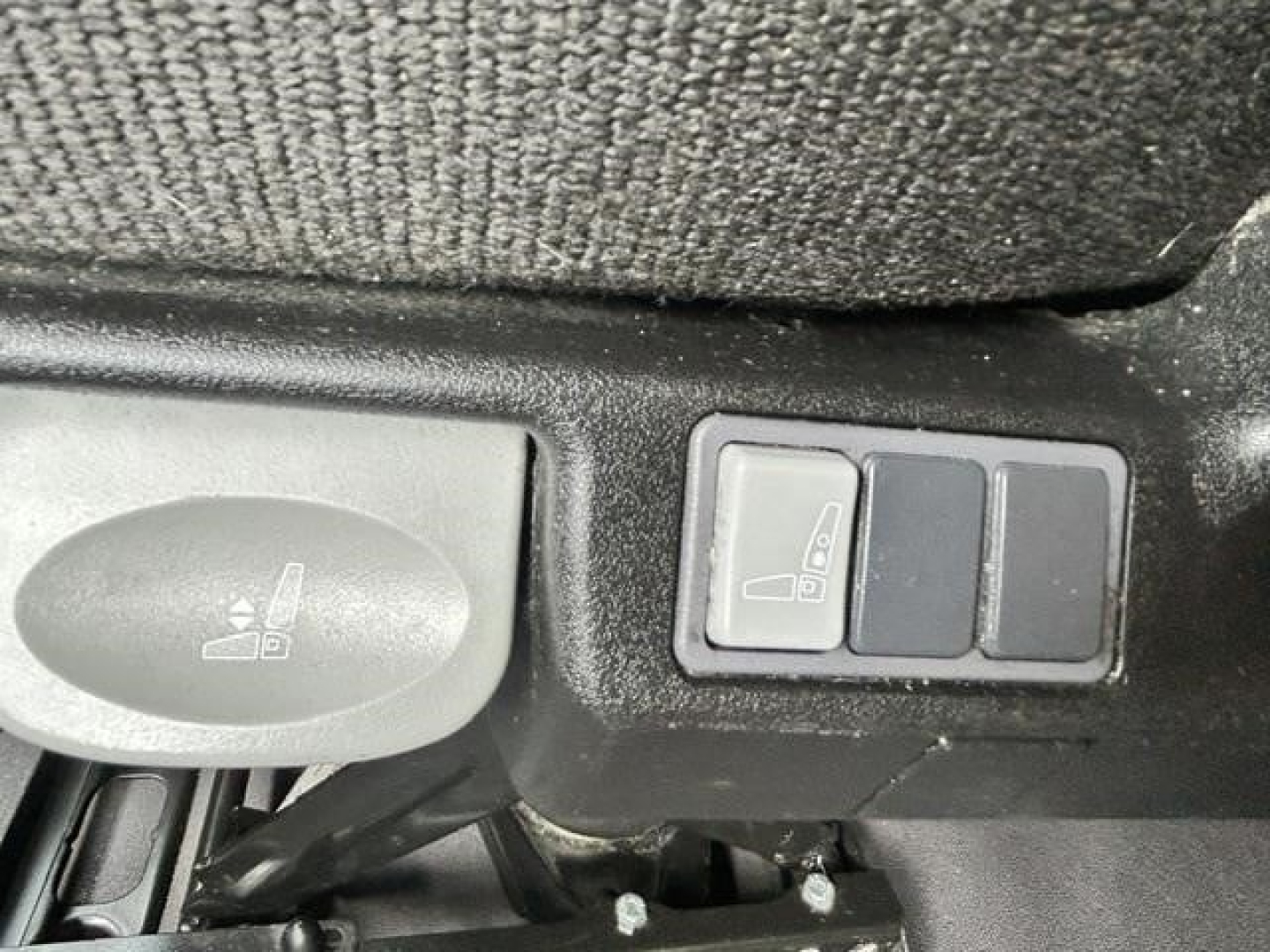 Cab interior showing window/mirror adjustment switch and a control pad near seat with two blank buttons.