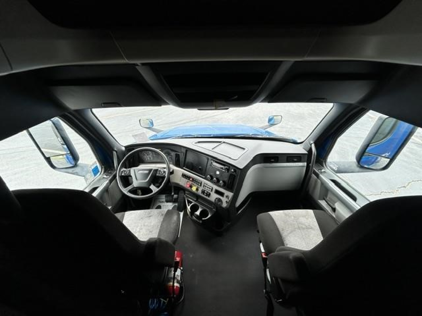 Cab interior of a 2022 Freightliner Cascadia 126 conventional sleeper showing steering wheel, dashboard, and front seats.
