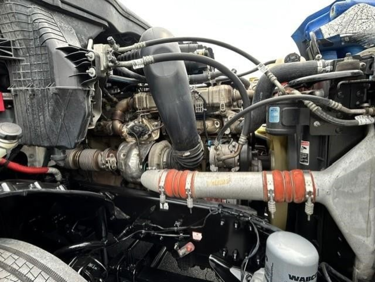 Freightliner Cascadia 126 engine bay showing diesel engine, hoses, and coolant reservoir.