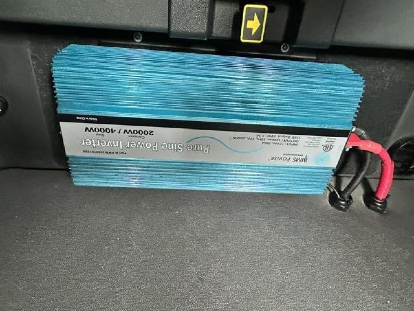 Blue blue-sleeved power inverter/rectifier unit mounted under dash with label; text includes 2300W 3000W input? (Note: exact text not fully legible) showing electrical module, wires with red/black connectors.