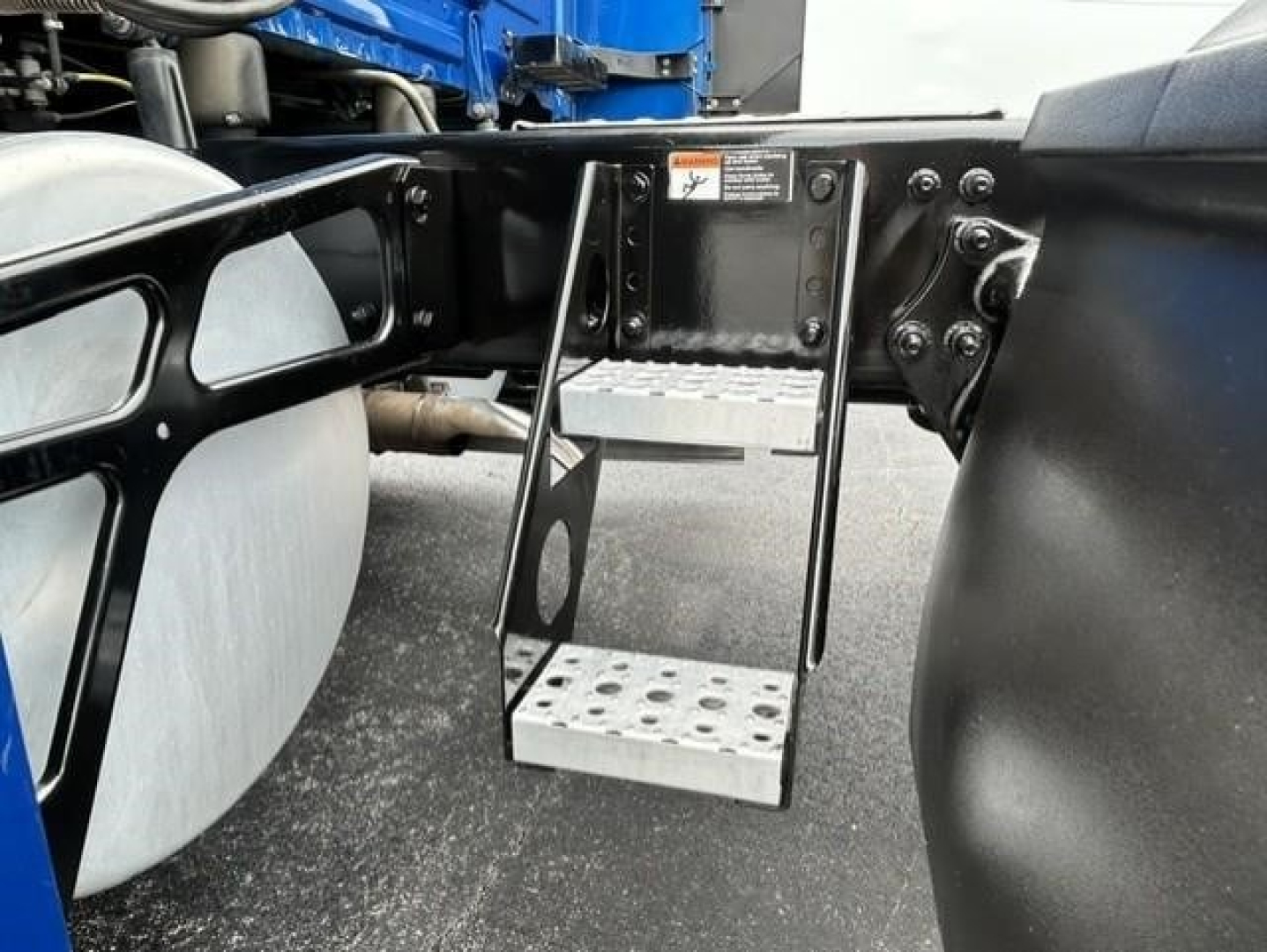Freightliner Cascadia 126 chassis area showing metal step with perforations and surrounding frame hardware.