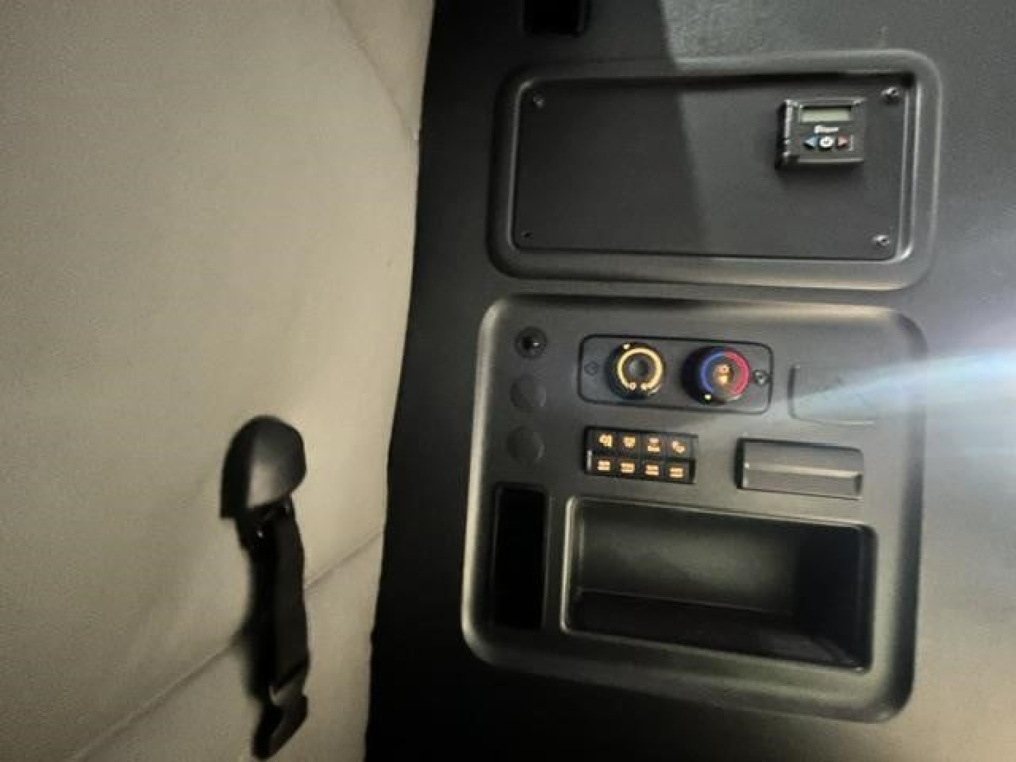 Cab interior dash area of a Freightliner Cascadia showing a small panel with a few gauges, a vent, and a storage slot.
