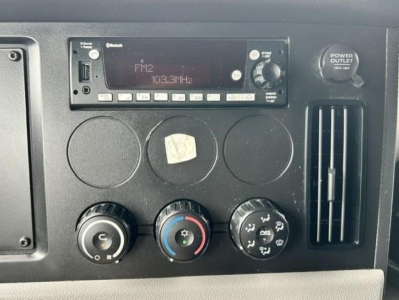Dashboard of a 2022 Freightliner Cascadia 126 showing FM2 radio display 103.3MHz, three control knobs, and a power outlet vent panel.