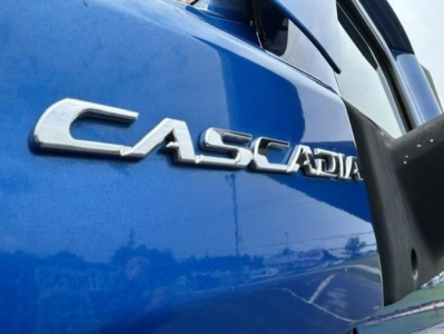Freightliner Cascadia badge on blue truck door showing 'CASCADIA' lettering.