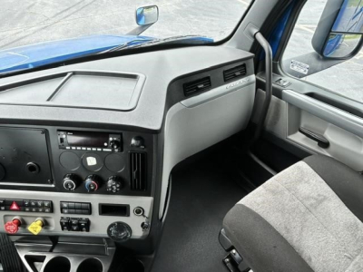 Truck cab interior of a 2022 Freightliner Cascadia showing dashboard, steering wheel area, and driver seat with controls and vents.
