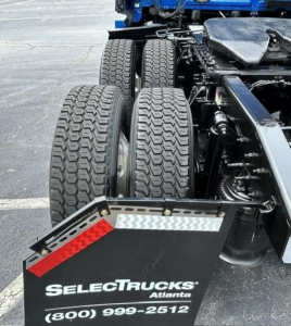 Truck rear undercarriage showing tandem wheels and mudflap with SelectTrucks Atlanta logo and contact number (800) 999-2512.