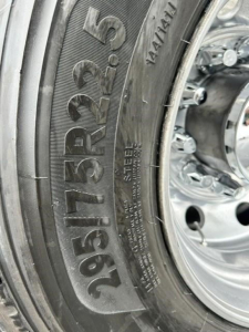 Tire sidewall with large numbers 225/70 R19.5 and steel wheel profile visible