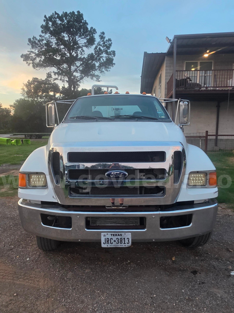 Front view of a white 2011 Ford F-750 vacuum truck showing chrome grille, bumper, large side mirrors, and Texas license plate JRC-3813.