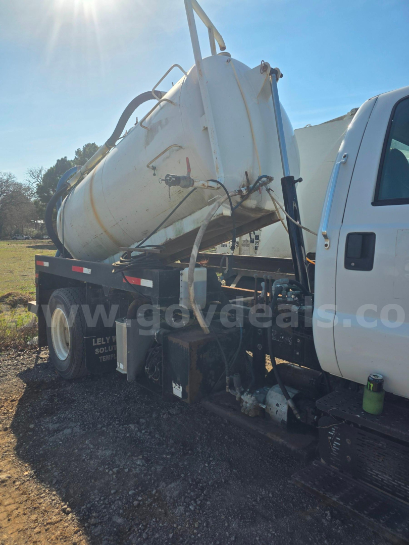 Truck side view showing a white vacuum tanker mounted on a white cab chassis. Visible text on the image includes a watermark and details like 'www.govdeals.com' on the tank area.