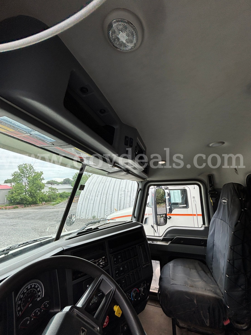 Cab interior of a 2020 Mack Granite dump truck showing steering wheel and driver's seat with dashboard and overhead console.