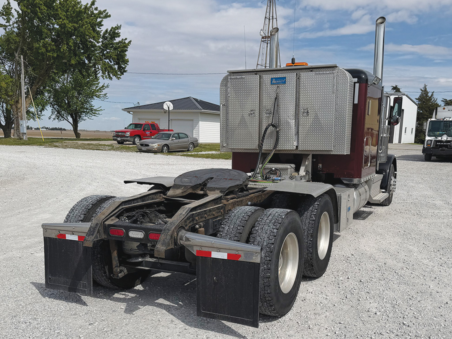 Peterbilt 389 extended hood truck from rear-quarter view showing sleeper cab and dual rear axles with fifth wheel and mud flaps.