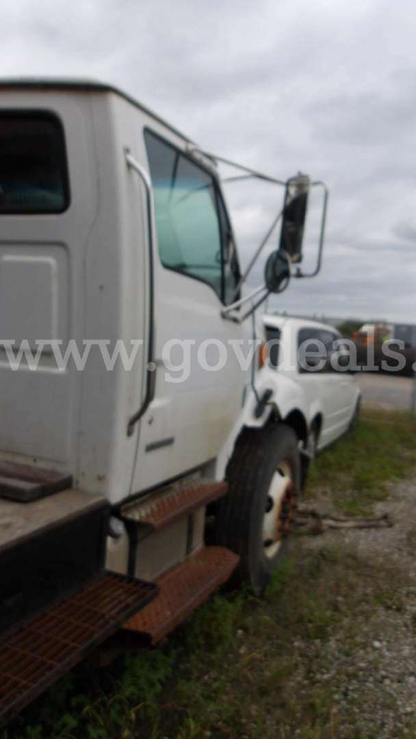 Truck cab side view showing Sterling Acterra grapple truck with white exterior and side steps.