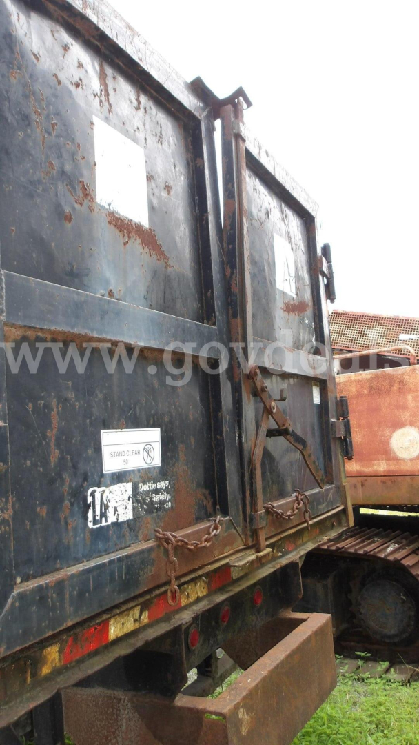 Truck rear view showing dark metal cargo doors with rust and chain latch.