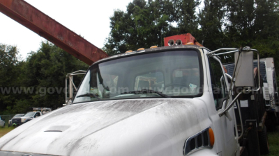 Truck cab of a 2006 Sterling Acterra grapple truck showing front windshield, side mirrors, and mounted grapple apparatus behind cab.