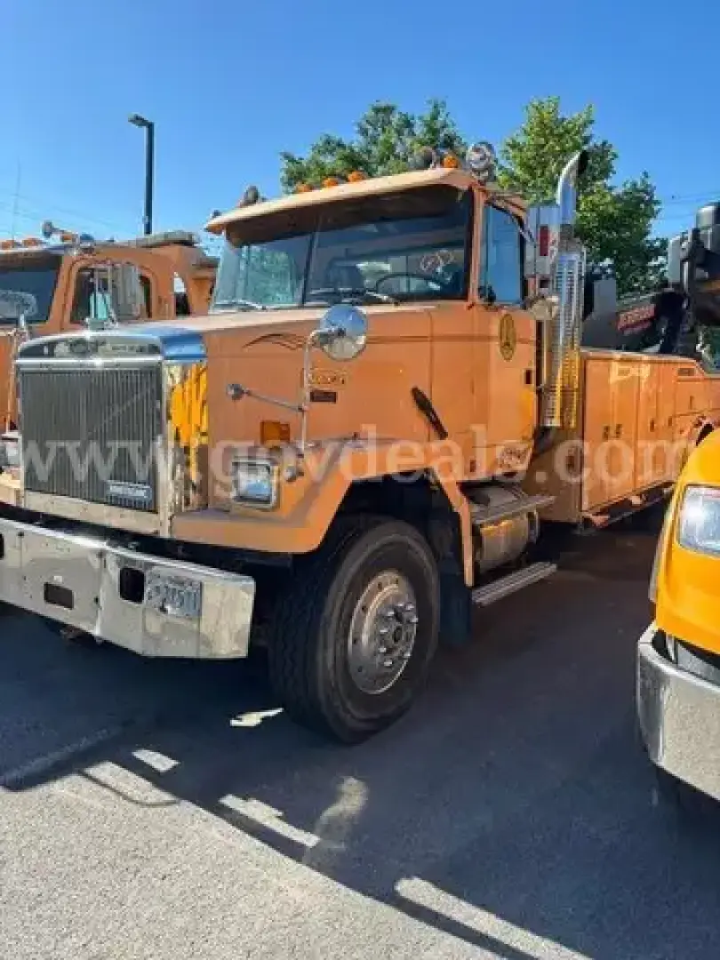 GMC tow truck in service showing front and driver side with orange cab and chrome grille.