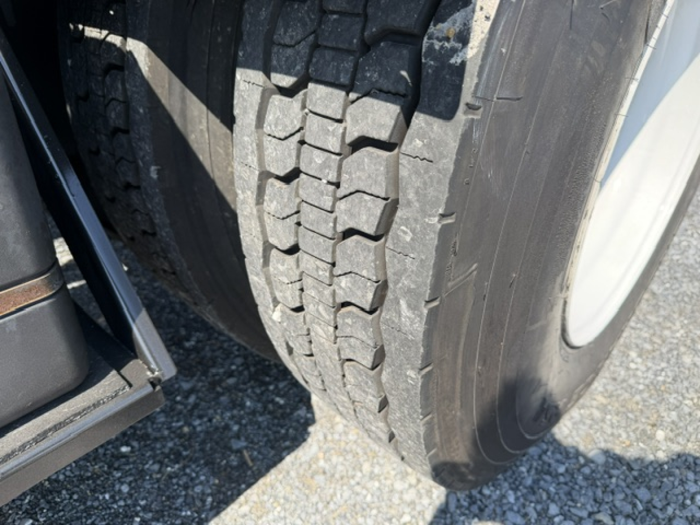 Truck tire close-up showing large tread pattern and wheel.