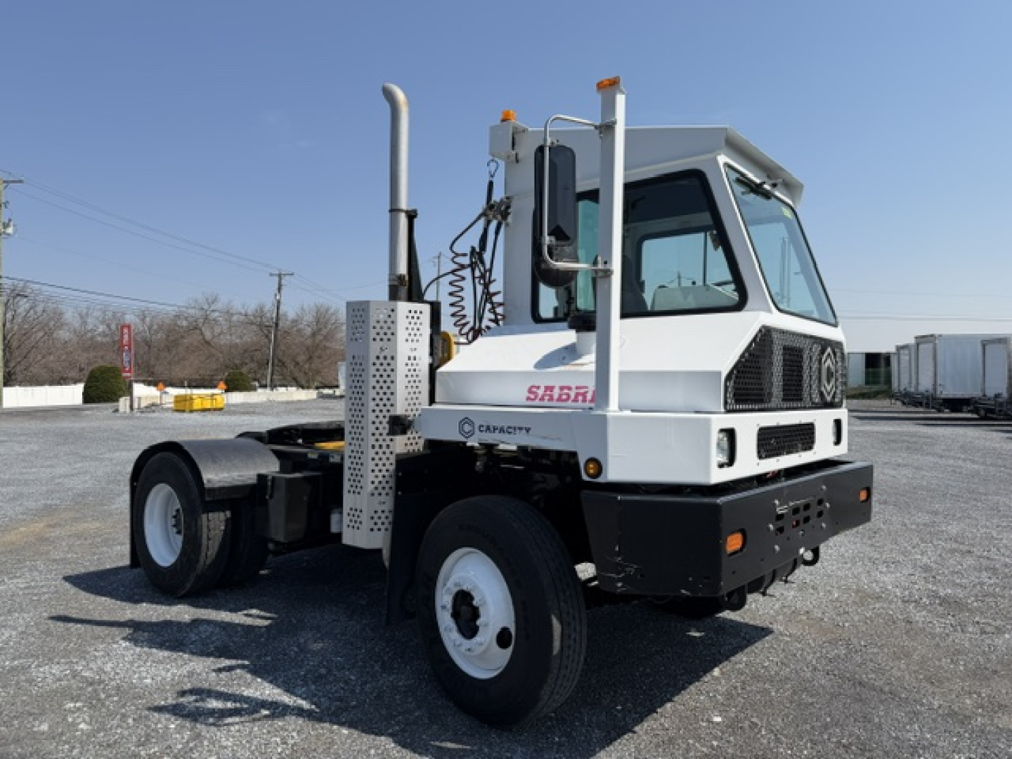 Truck cab of a 2018 Capacity Sabre yard truck showing front and side, with fuel/exhaust stack, white cab, black bumper, and Sabre logo on door.