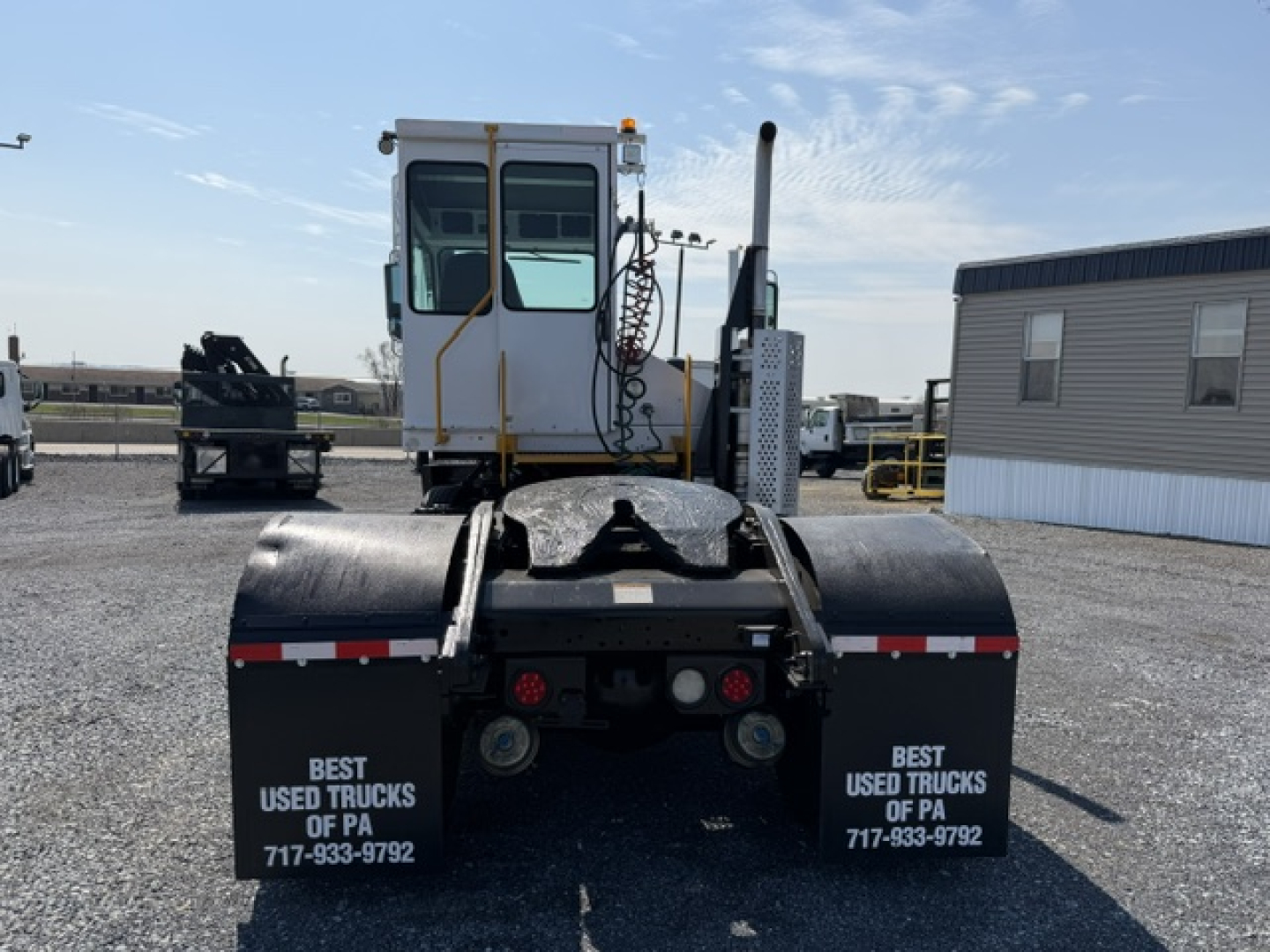 Tractor-trailer chassis view showing a rear cab and fifth-wheel hitch assembly with dual rear lights and safety rails.
