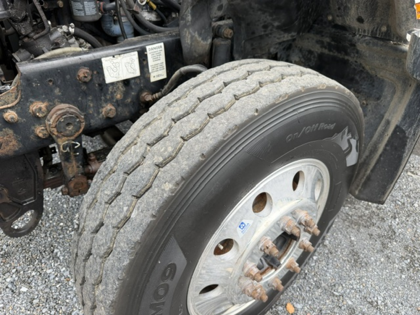 Truck front wheel and engine bay of a 2007 Mack CV713 dump truck showing tire, hub, and wheel assembly.