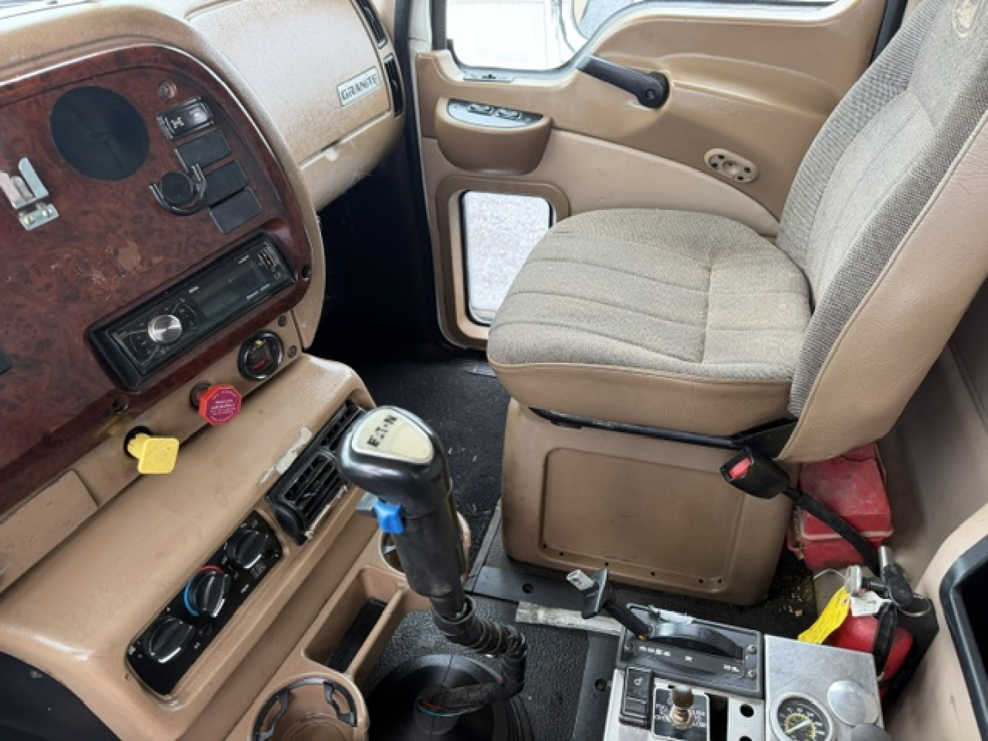Interior of a 2007 Mack CV713 cab showing steering wheel area, dashboard with wood panel, gear shifter, and seat. Text visible includes no explicit part numbers in view.
