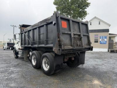 Dump truck rear and left side showing black MDT Mack CV713 dump body with dual rear axles and sixth-wheel configuration.
