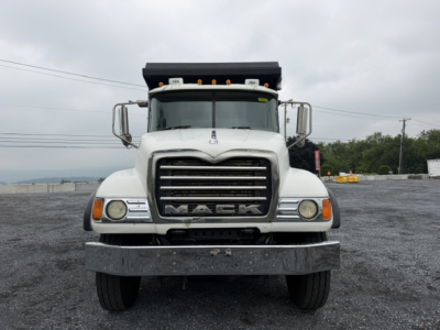 Front view of a white 2007 Mack CV713 dump truck with large grille, Mack emblem, headlights, bumper, and raised dump bed visible.