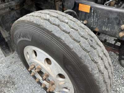 Tire and front wheel area of a 2007 Mack CV713 dump truck showing a Hankook tire and wheel assembly.