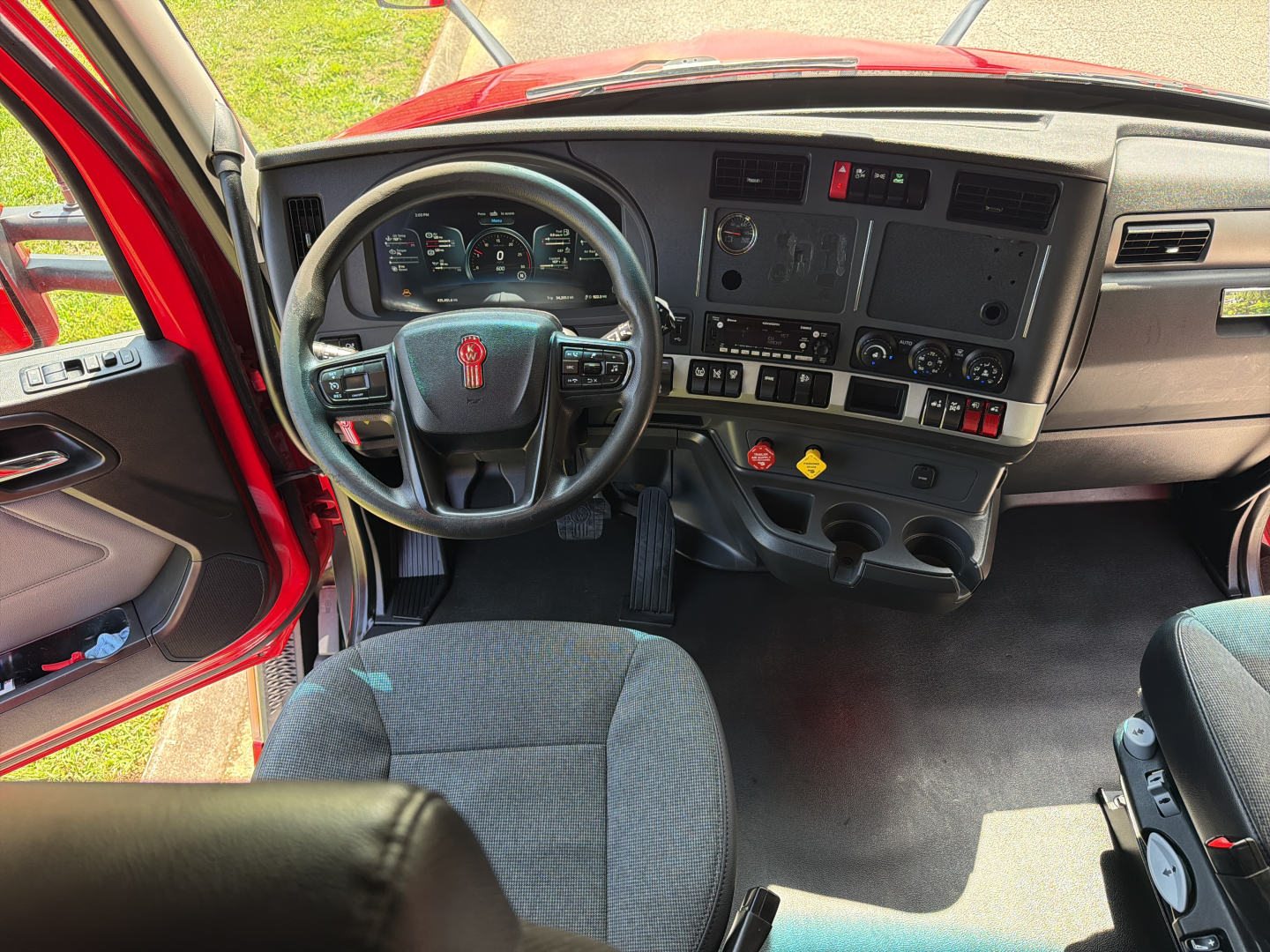 Kenworth T680 cab interior showing steering wheel, dashboard with gauges, control switches, and center console.