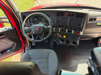 Kenworth T680 cab interior showing steering wheel, dashboard with gauges, control switches, and center console.