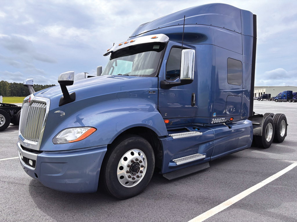 Truck cab showing 2020 International LT625 with blue paint, large sleeper, chrome mirrors, and dual rear axles.