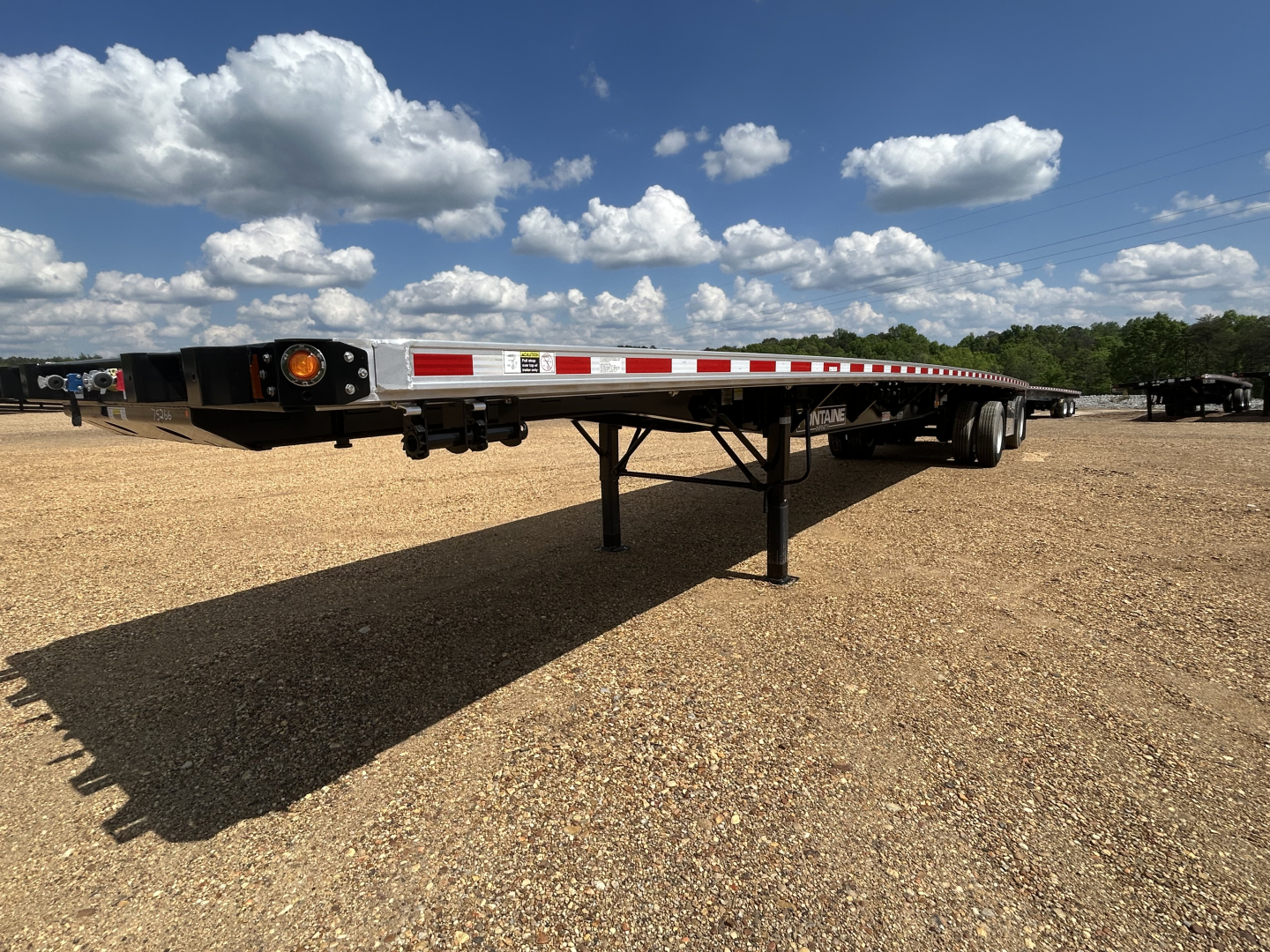Fontaine 48' combo spread trailer low-angle side view showing undercarriage with landing gear, reflective safety stripes, and rear lights.