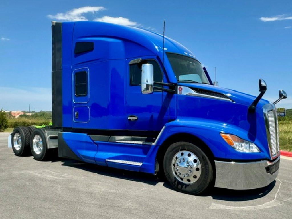 Kenworth T680 conventional sleeper truck in blue, side view showing cab, wheel, and chrome bumper.
