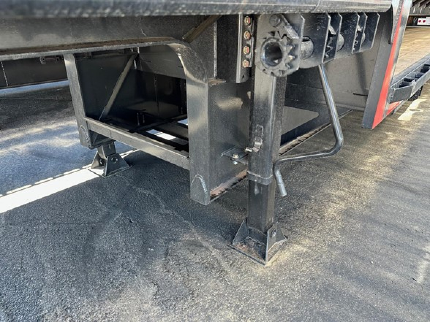 Trailer landing gear and undercarriage of a drop deck trailer showing support legs and frame with label text partially visible.