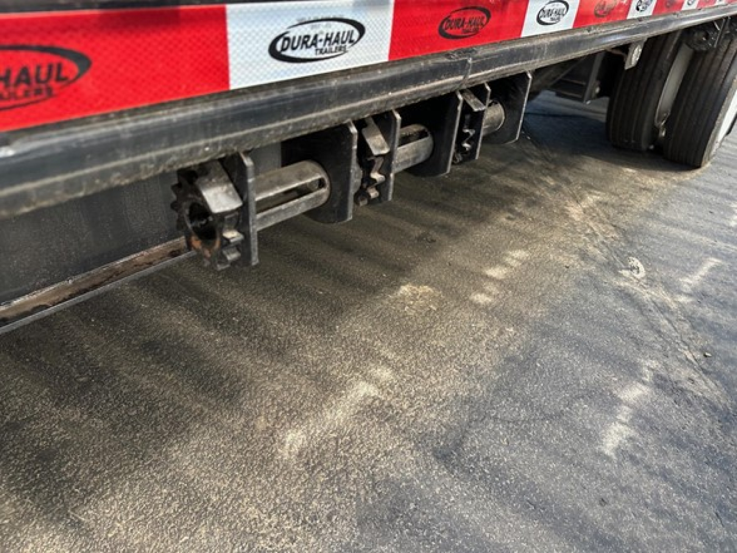 Trailer underside showing drop deck component latches and frame with Dura-Haul branding along side.