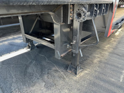 Trailer landing gear and undercarriage of a drop deck trailer showing support legs and frame with label text partially visible.