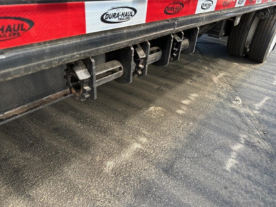 Trailer underside showing drop deck component latches and frame with Dura-Haul branding along side.