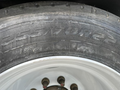 Tire and wheel of a trailer showing the tread and rim detail with visible tire markings.