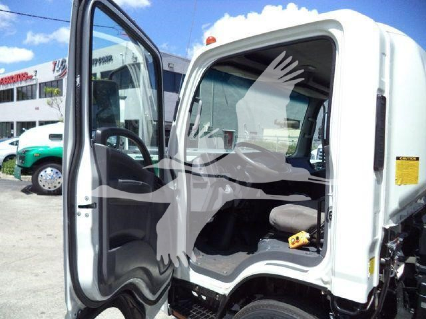 Isuzu NPRR dump truck cab interior visible with open driver door and steering wheel.