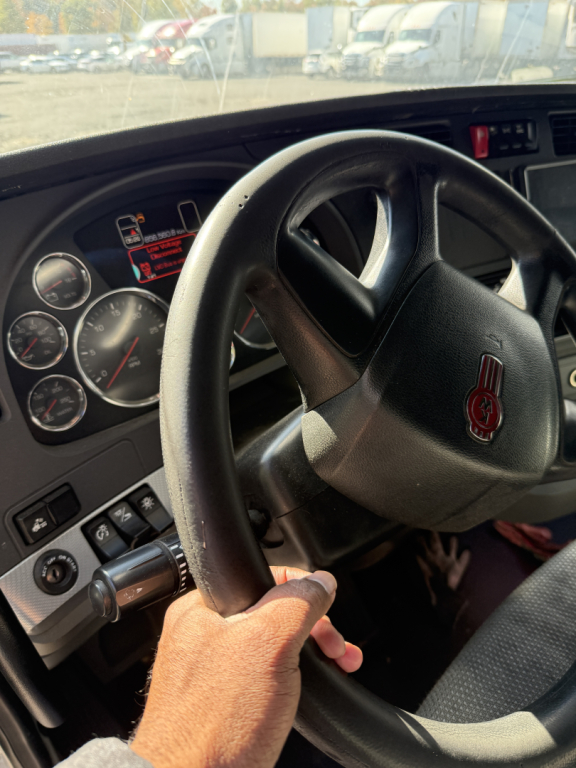 Kenworth T680 steering wheel and dashboard view; gauges and controls visible.