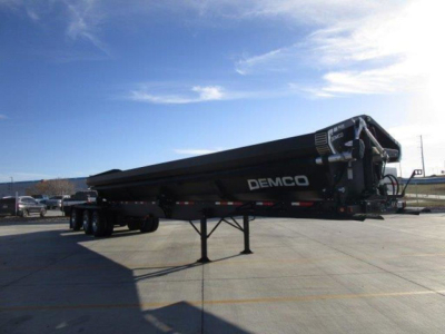Demco dump trailer in-service view showing side profile with DEMCO branding on the tank.