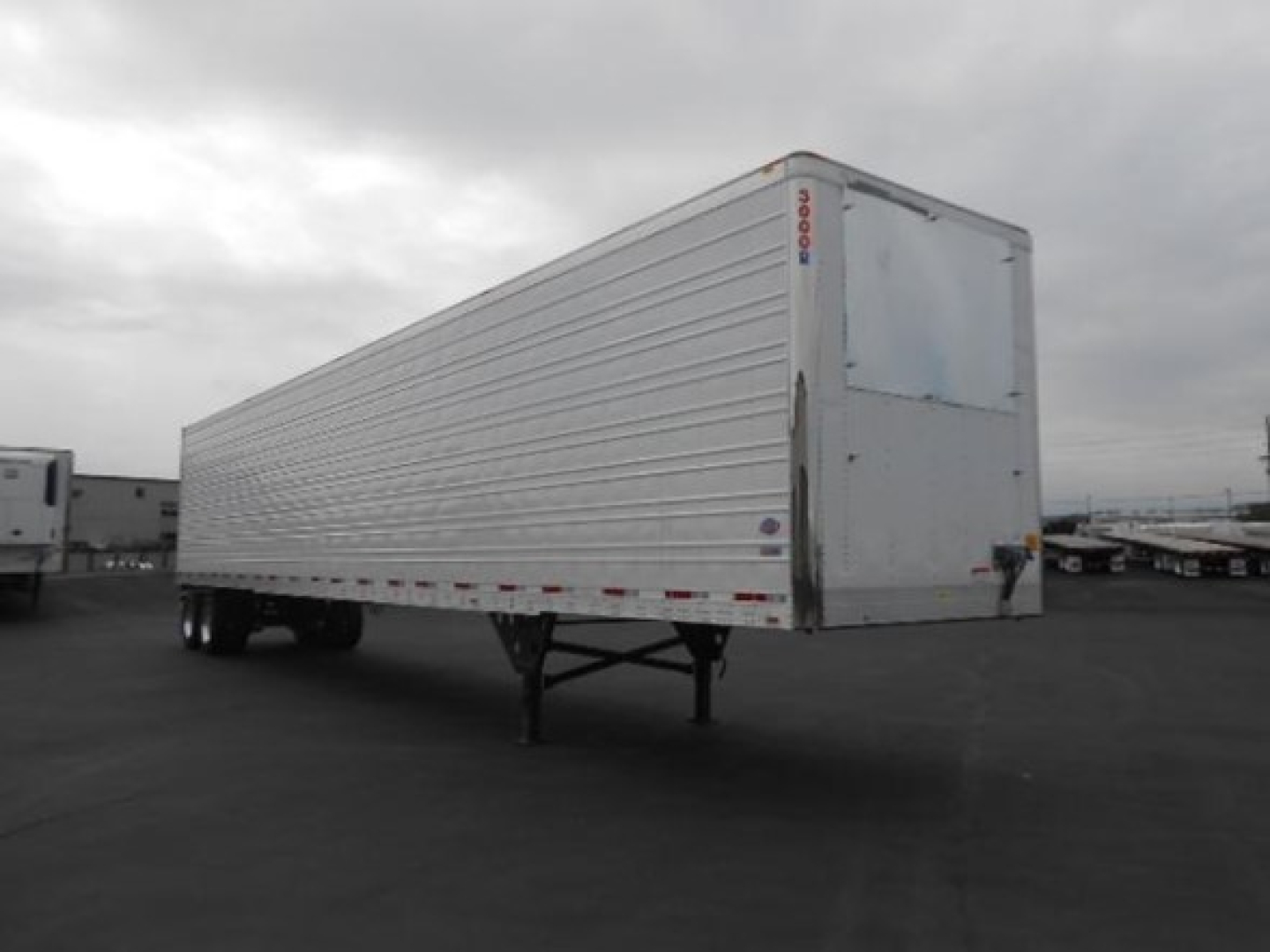 Utility 3000R trailer side and rear view showing corrugated aluminum walls, standard roll-up rear doors, and landing gear. Side text not legible.