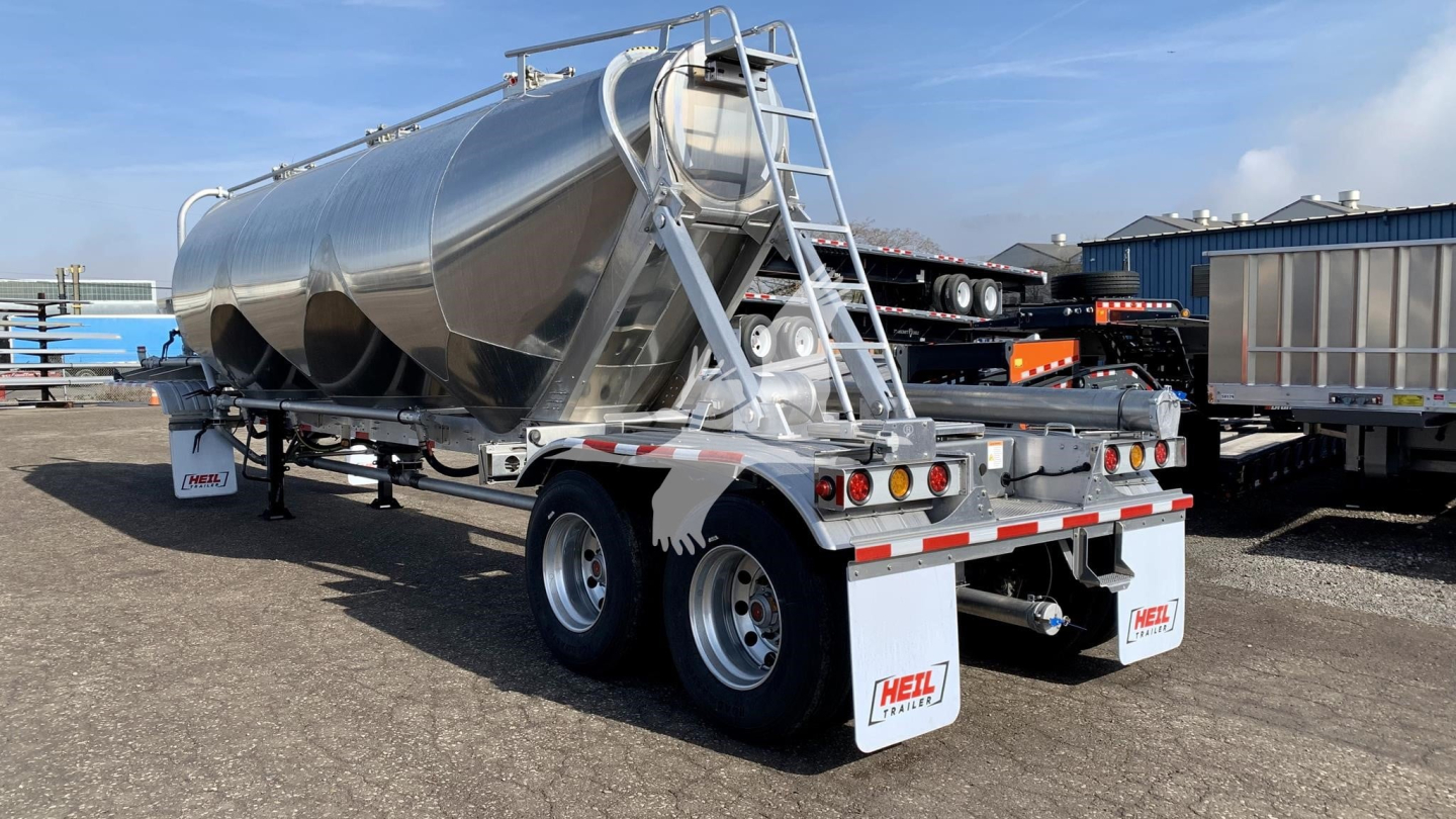 Heil cement mixer trailer/tanker in silver with dual wheels, rear lights and ladders; side text unreadable, but shows Heil brand mud flaps.