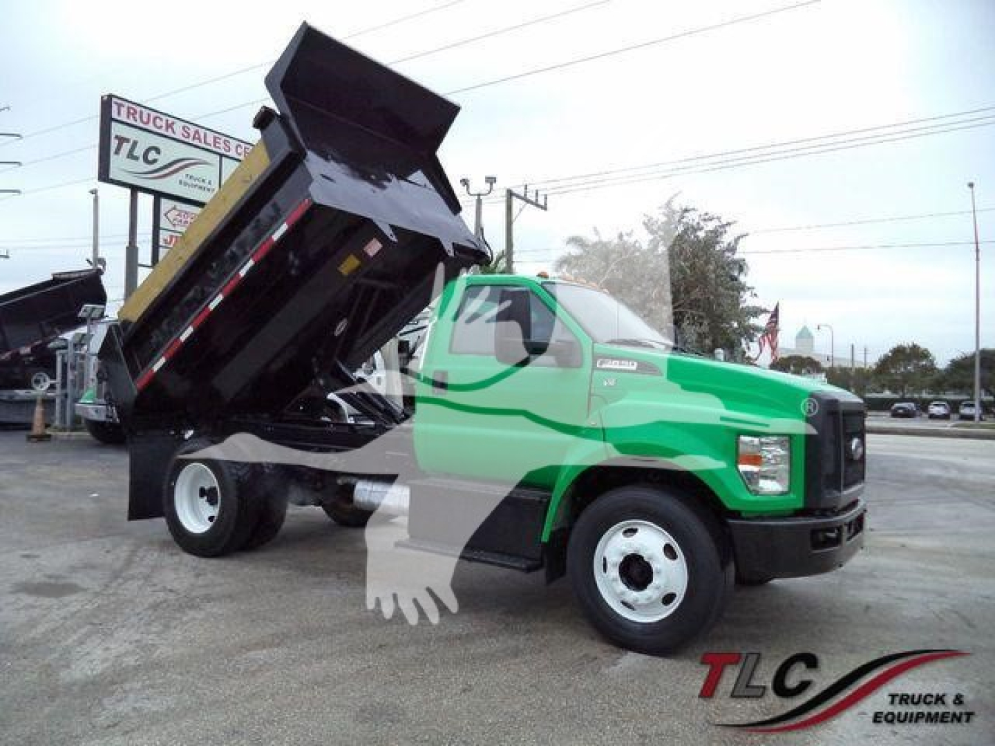 Truck bed dump rear angle view showing green Ford F-650 dump truck with raised bed and hydraulic mechanism.