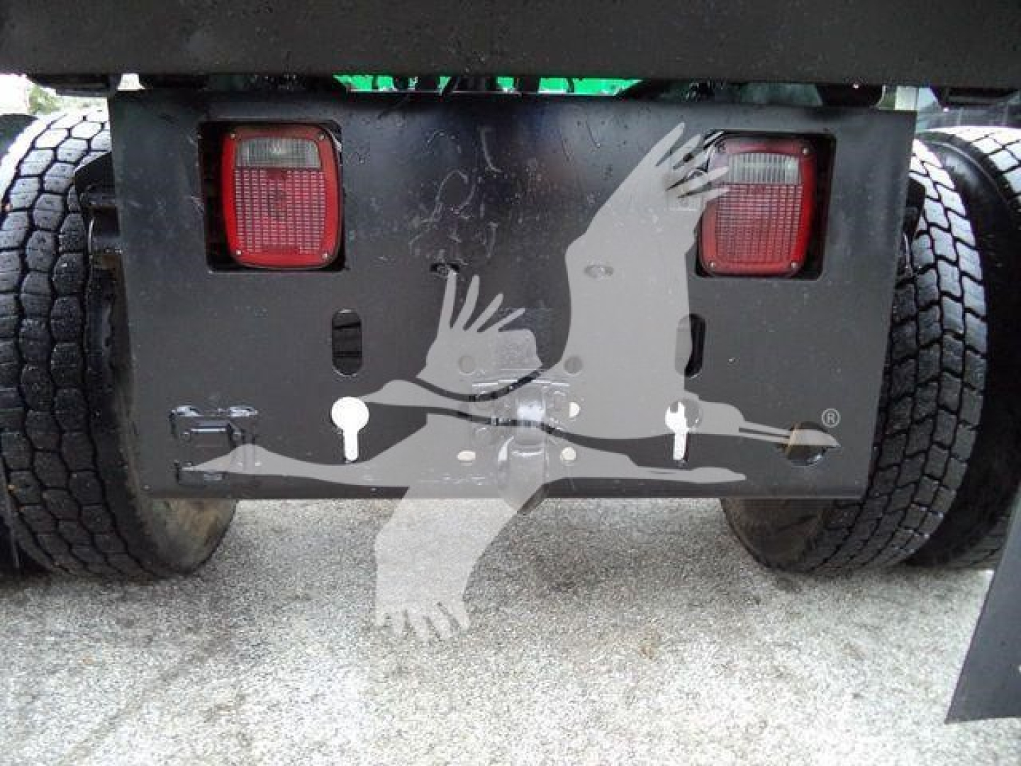 Rear view of a Ford F650 SD truck showing taillights, bumper with warning labels and hitch area with two round reflector lights.